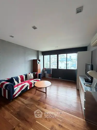 Spacious living room with modern decor and large windows offering city views.