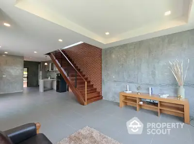 Spacious living area with polished concrete floors, an elegant brick staircase, and a modern open layout leading to a sleek kitchen.