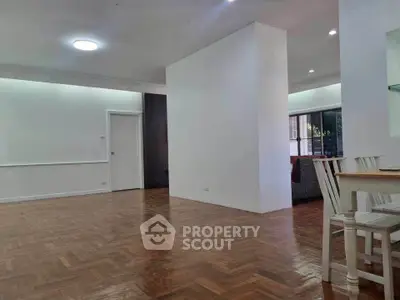 Spacious open-plan living area with wooden flooring and modern dining set.