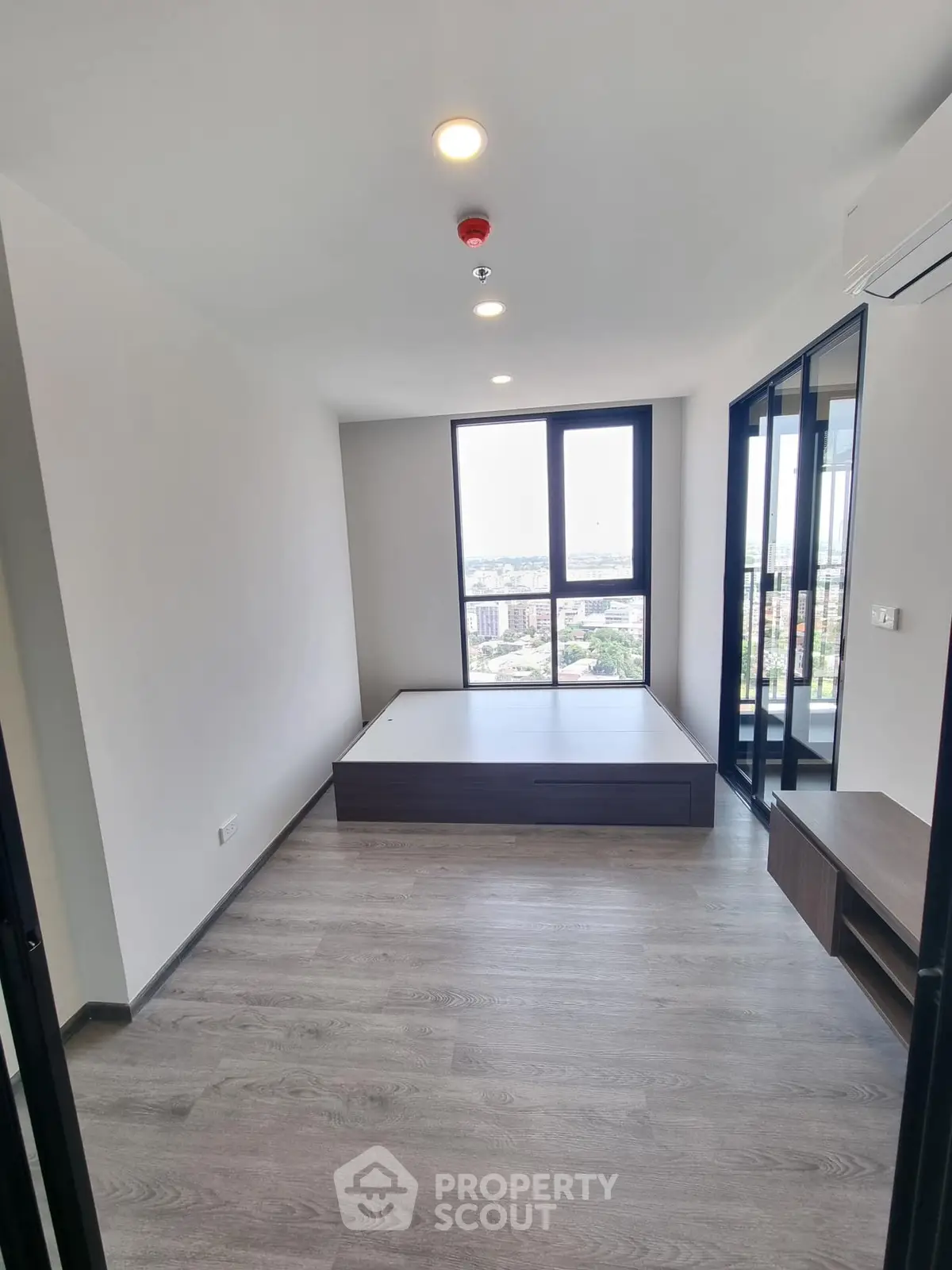 Spacious and bright modern living room with large windows offering a panoramic city view, sleek flooring, and a raised platform for versatile use.