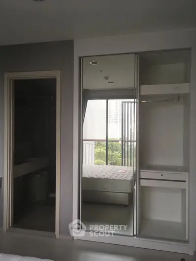 Modern bedroom with mirrored closet and balcony view in urban apartment
