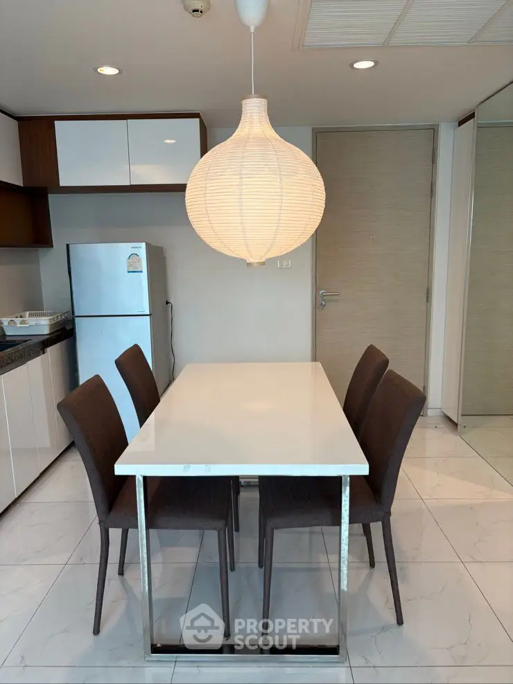 Modern kitchen with sleek dining table and stylish chairs under elegant pendant light.