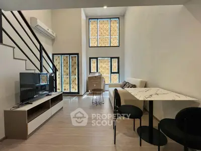 Modern living room with high ceilings, stylish furniture, and large windows for natural light.