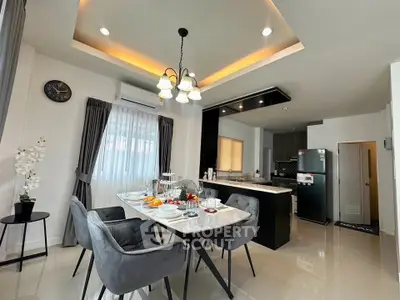 Modern dining area with elegant lighting and open kitchen layout, featuring sleek appliances and stylish decor.