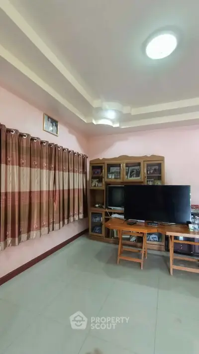 Cozy living room with TV and wooden furniture, ideal for relaxation.