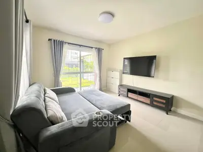 Spacious living room with modern sofa bed and large TV, bright natural light from window.