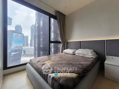 Modern bedroom with large window offering stunning cityscape views in a high-rise apartment.