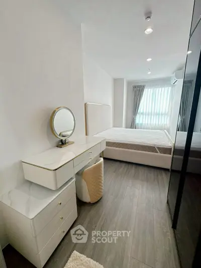 Modern bedroom with elegant vanity and natural light, featuring sleek design and cozy ambiance.