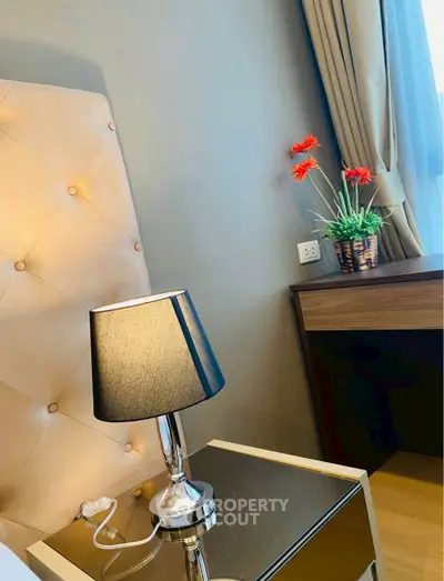 Elegant bedroom corner with stylish lamp and floral decor, perfect for modern living.