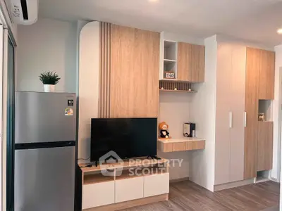 Modern living room with sleek wooden cabinetry and flat-screen TV, featuring a stylish fridge and air conditioning.