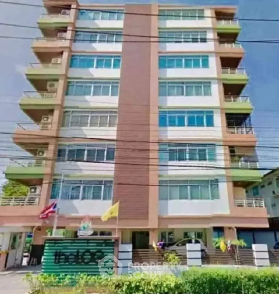Modern multi-story residential building with balconies and flags, ideal urban living.