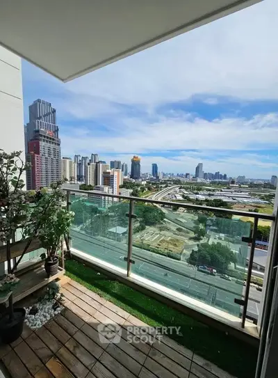 Stunning cityscape view from a modern balcony with glass railing and greenery.