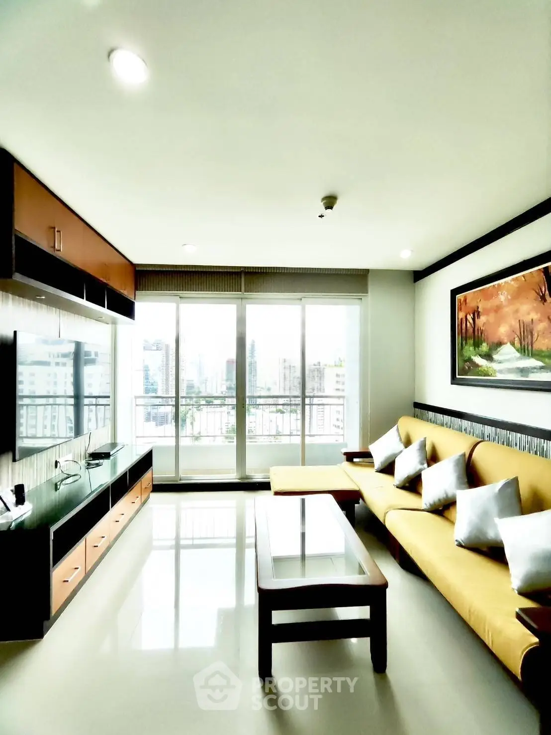 Spacious living room with modern decor and city view, featuring a large sofa and entertainment unit.