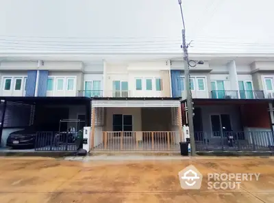 Modern townhouse exterior with covered parking and balcony in a suburban neighborhood.