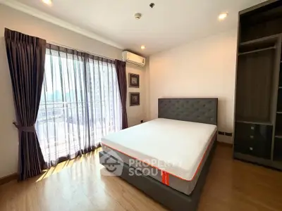 Spacious bedroom with modern decor and large window offering natural light.