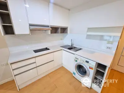 Modern kitchen with sleek white cabinetry and built-in washing machine