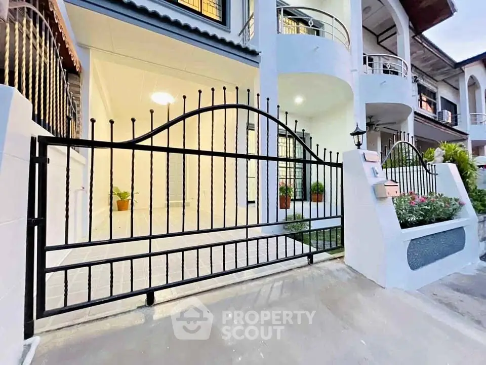 Charming townhouse entrance with elegant wrought iron gate and lush garden.