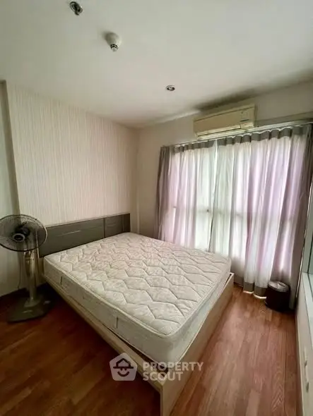 Cozy bedroom with natural light, featuring a comfortable bed and air conditioning, perfect for relaxation.