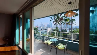 Spacious balcony with city view and cozy seating area in modern apartment.