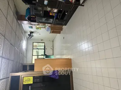 Spacious tiled room with wooden cabinets and ample natural light, ideal for versatile use.