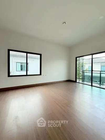 Spacious empty room with large windows and wooden flooring in modern home