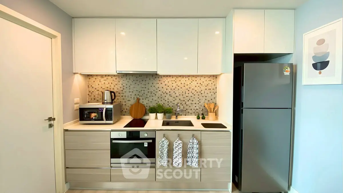Modern kitchen with sleek cabinets, mosaic backsplash, and stainless steel appliances.