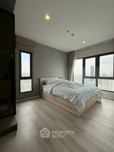 Spacious bedroom with large windows offering stunning city views