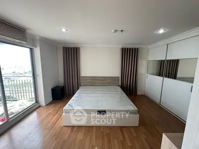 Spacious bedroom with large window and modern design in a high-rise apartment.