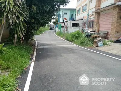 Charming residential street with lush greenery and modern buildings, ideal for peaceful living.