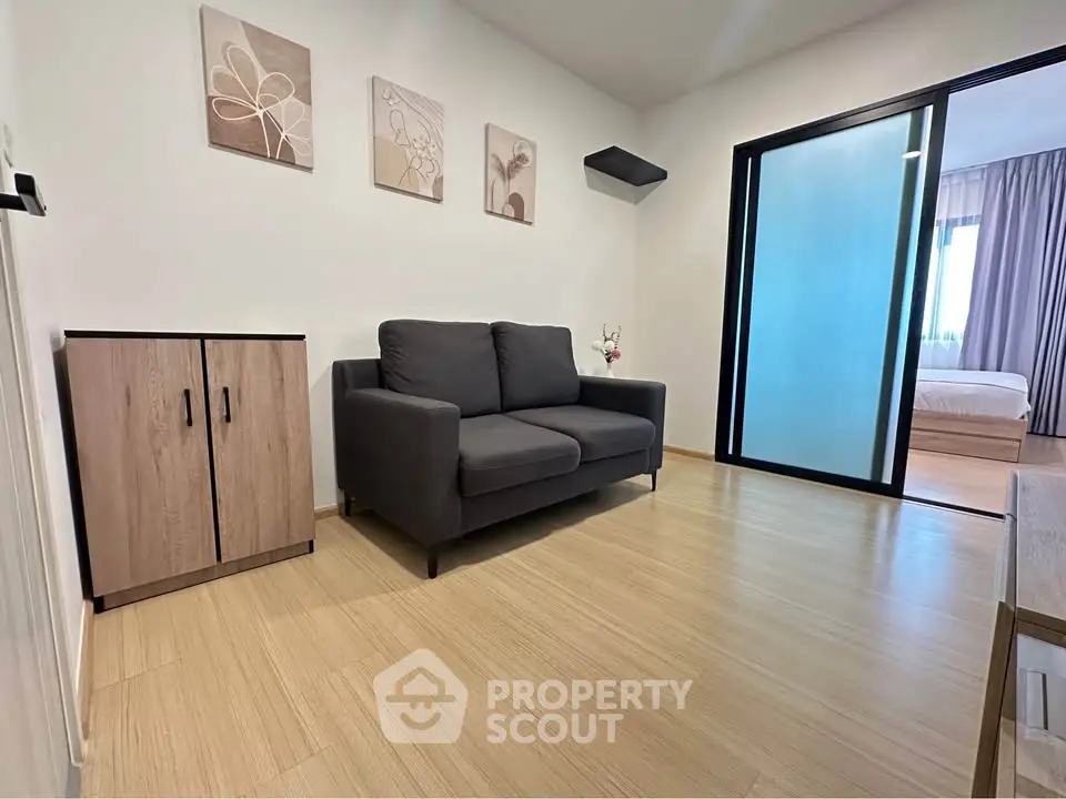 Modern living room with cozy sofa and sliding glass door leading to bedroom.