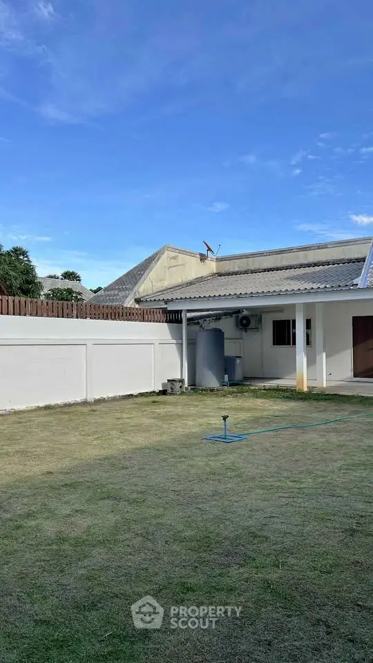 Spacious backyard with lush lawn and clear blue sky, perfect for outdoor activities.