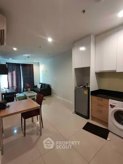 Modern open-plan living room with kitchen, featuring sleek furniture and appliances.