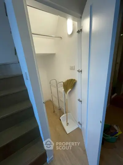 Compact storage space under stairs with broom and shelving unit