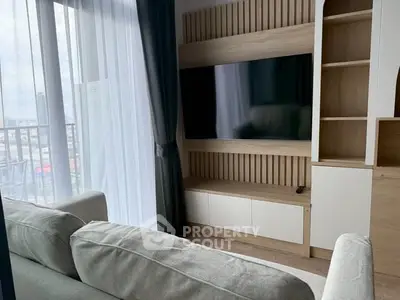 Modern living room with large TV and stylish furniture, featuring a cozy ambiance and natural light.