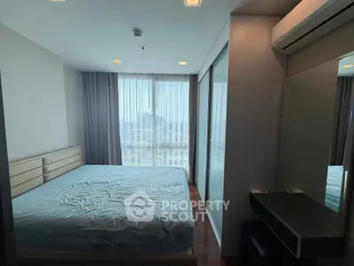 Spacious bedroom with large windows and modern furnishings in a high-rise apartment.