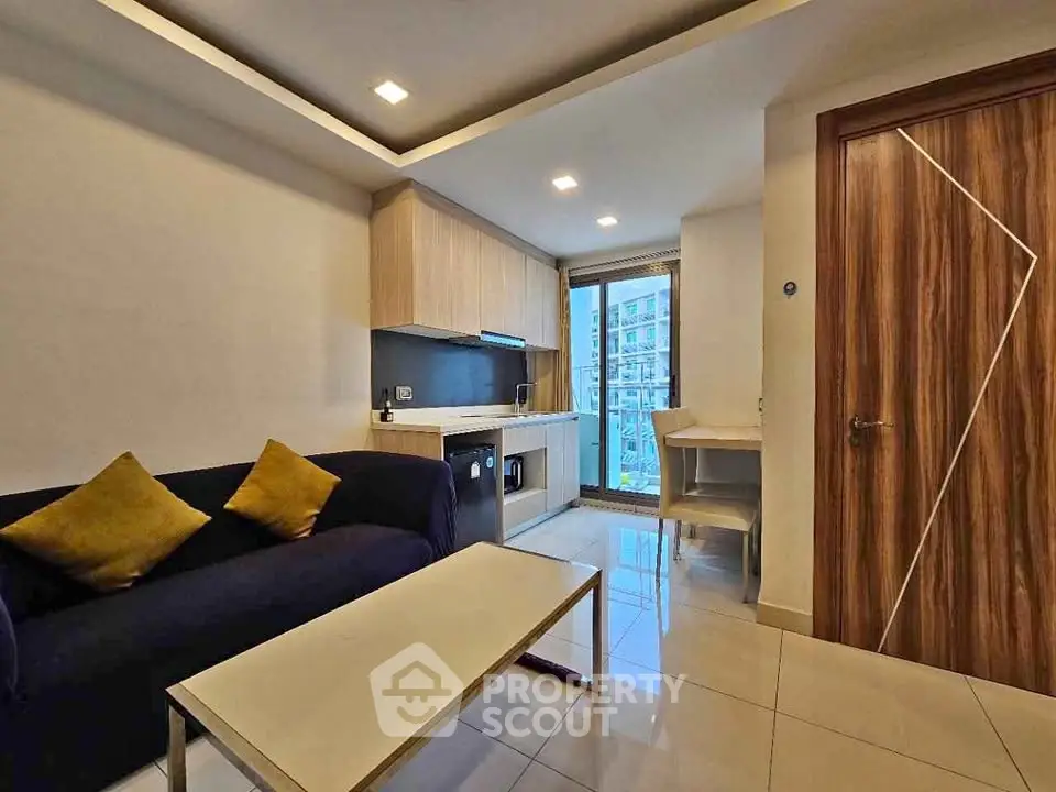 Modern living room with sleek furniture and open kitchen layout, featuring a washing machine and stylish decor.