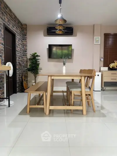 Modern dining area with wooden table and chairs, stylish decor, and wall-mounted TV.