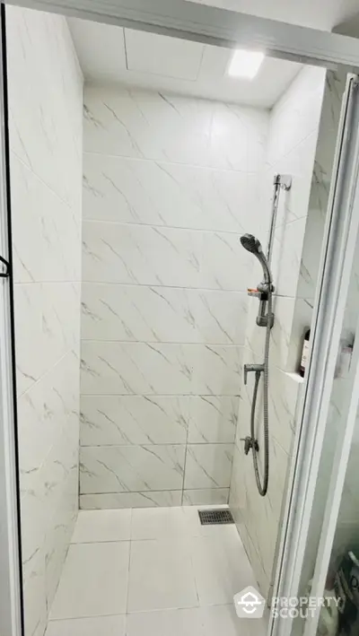 Modern bathroom shower area with sleek white tiles and contemporary fixtures.