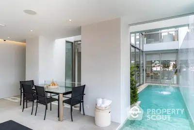 Luxurious modern dining area with glass walls overlooking a private pool, perfect for entertaining.