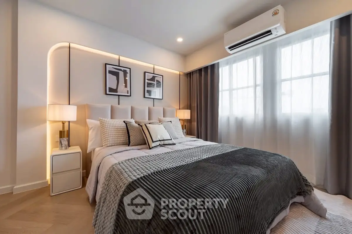 Modern bedroom with stylish decor and natural light, featuring a cozy bed and elegant lighting.