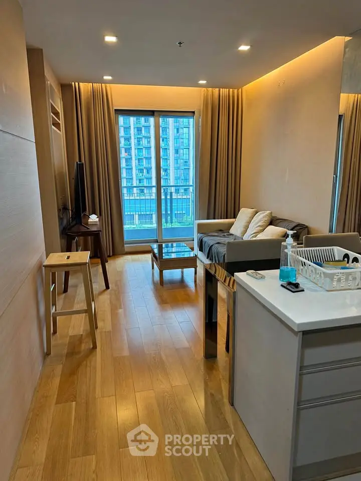 Modern living room with wooden flooring and large windows in a high-rise apartment.
