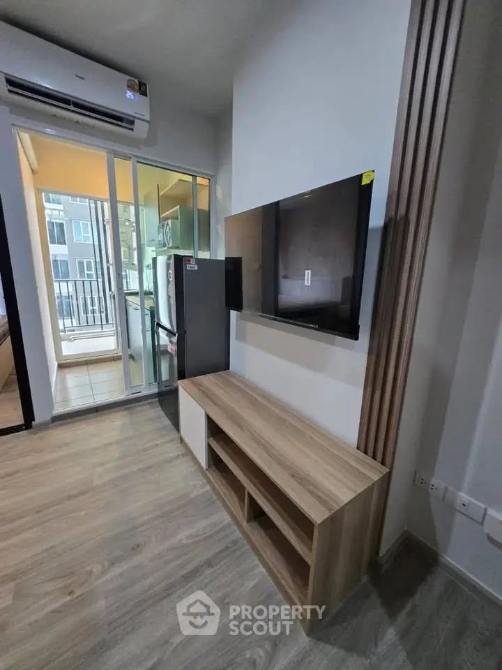 Modern apartment interior with sleek TV setup and balcony view