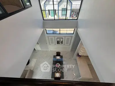 Elegant modern living room with high ceiling and large windows, showcasing a stylish dining area and chic decor.
