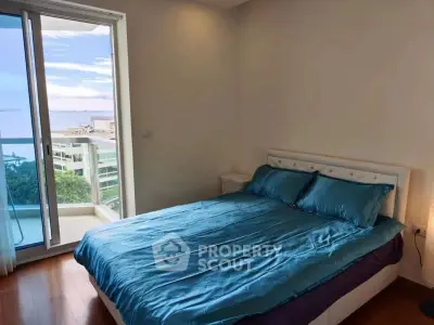 Cozy bedroom with ocean view and balcony access in modern apartment