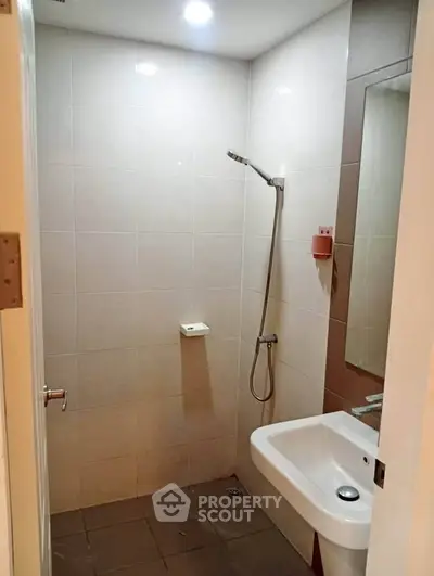 Compact bathroom with modern shower and sink in a real estate property.