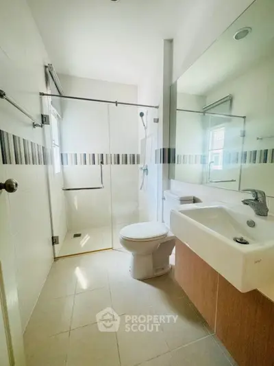 Modern bathroom with glass shower and sleek fixtures in bright natural light.