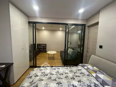 Modern bedroom with glass partition and cozy living area, featuring stylish decor and ample lighting.