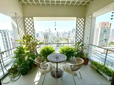 Stunning balcony with city skyline view, lush greenery, and cozy seating area.