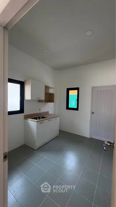 Minimalist kitchen with sleek cabinetry and tiled flooring in a modern home.