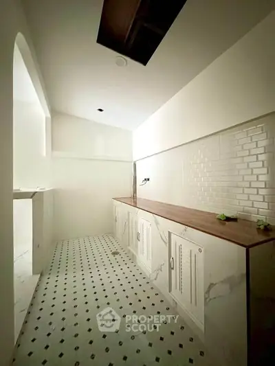 Elegant kitchen with white cabinetry and marble flooring, featuring a sleek wooden countertop and subway tile backsplash.